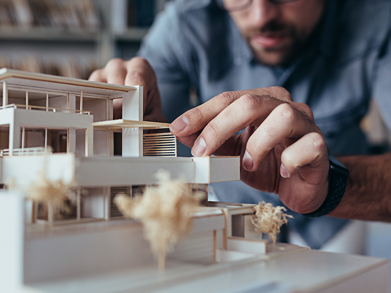 An architect Working on a Building Prototype Made of White Wood.