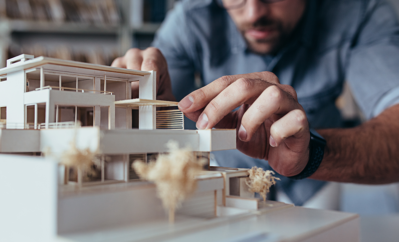 An architect Working on a Building Prototype Made of White Wood