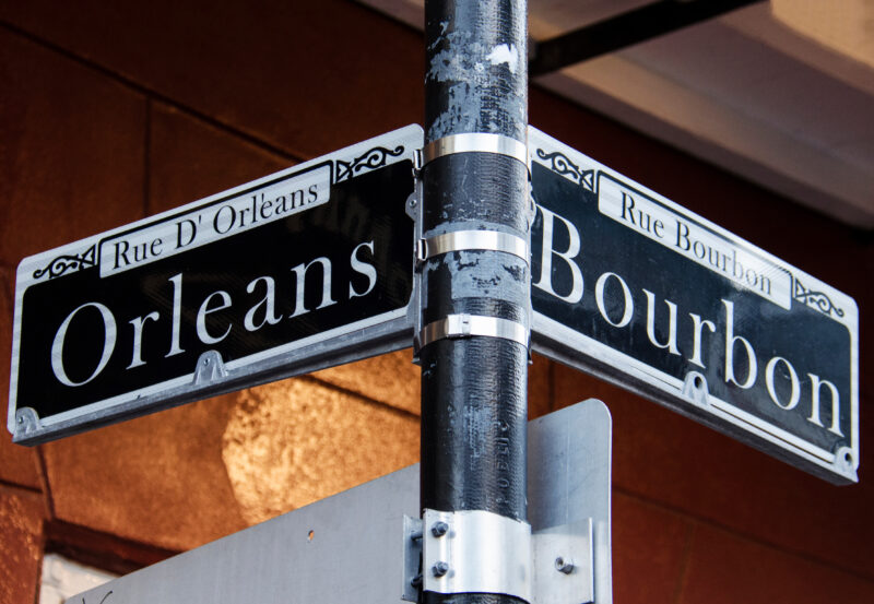 Street corner signs for Rue D' Orleans and Rue Bourbon in New Orleans, LA.