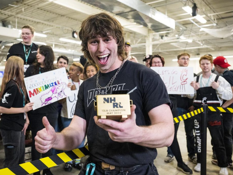 Jake Hoffmann posing with his "Golden Dumpster" award filled with cash after winning NHRL's "May The Bots Be With You" combat robotics (BattleBots) competition.