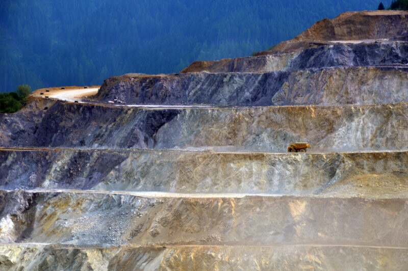 A dump truck travels across one of the giant layers of the Erzberg Mine’s mountain. It looks extremely small compared to the mountain.