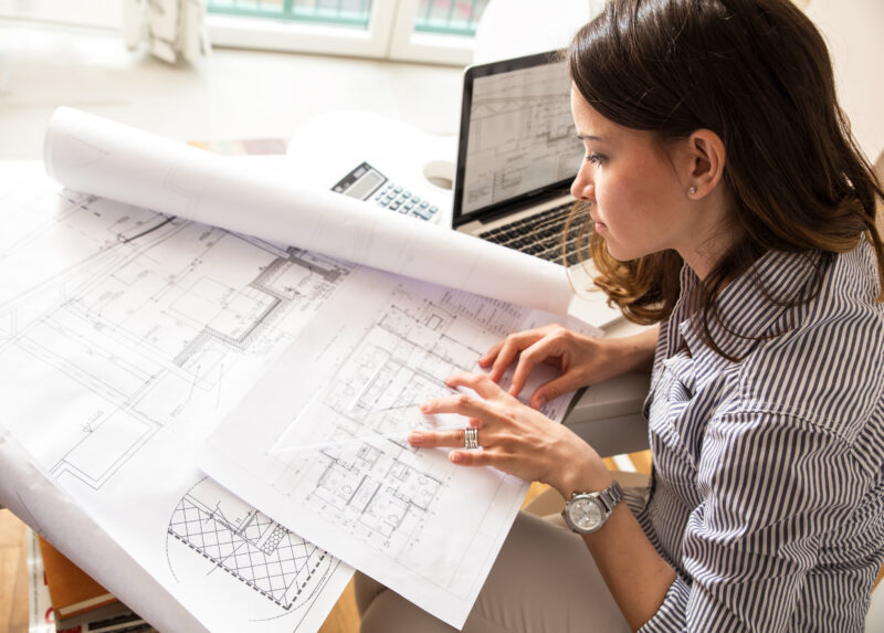 A woman looking over architecture materials at a desk. How to Market to Architects and Specifiers Online